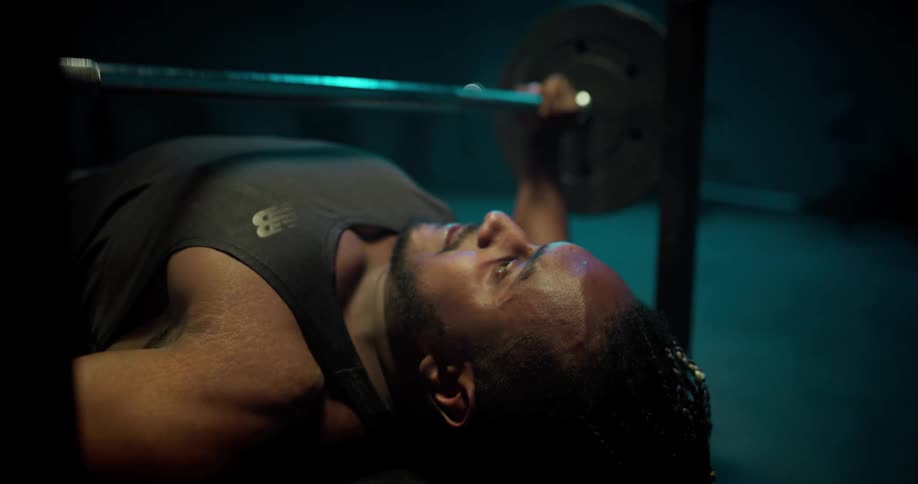A man is lying on a bench press working out lifing weights