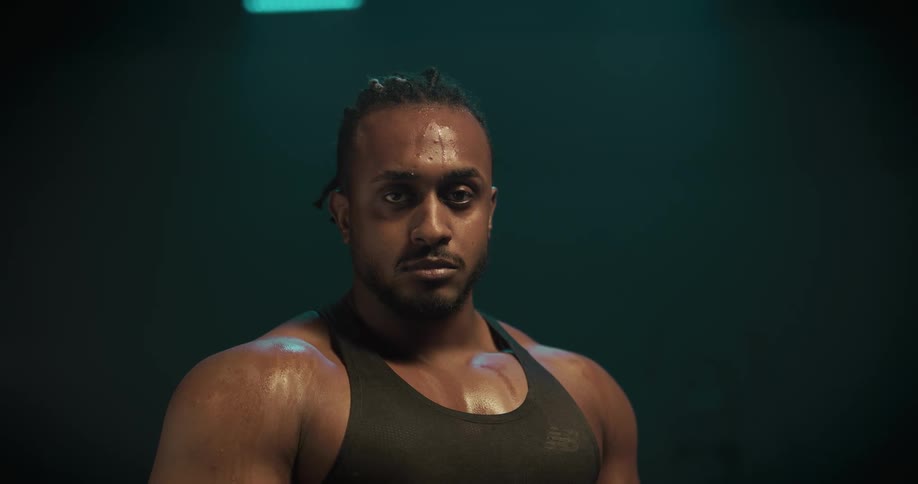 Young strong muscular man covered in sweat looking at the camera