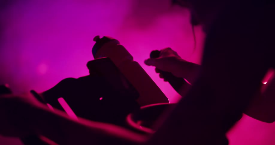 A woman works out on an exercise bike in a pink tinged room