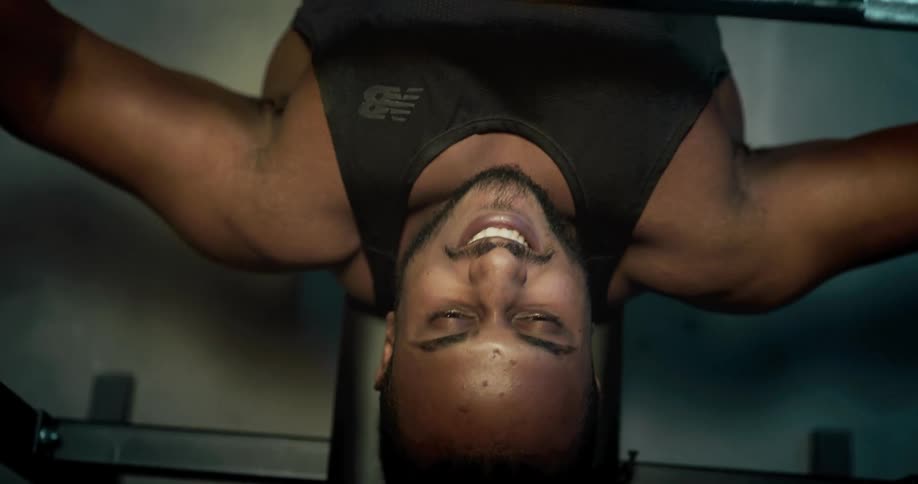 A man is lying on a bench press working out lifing weights
