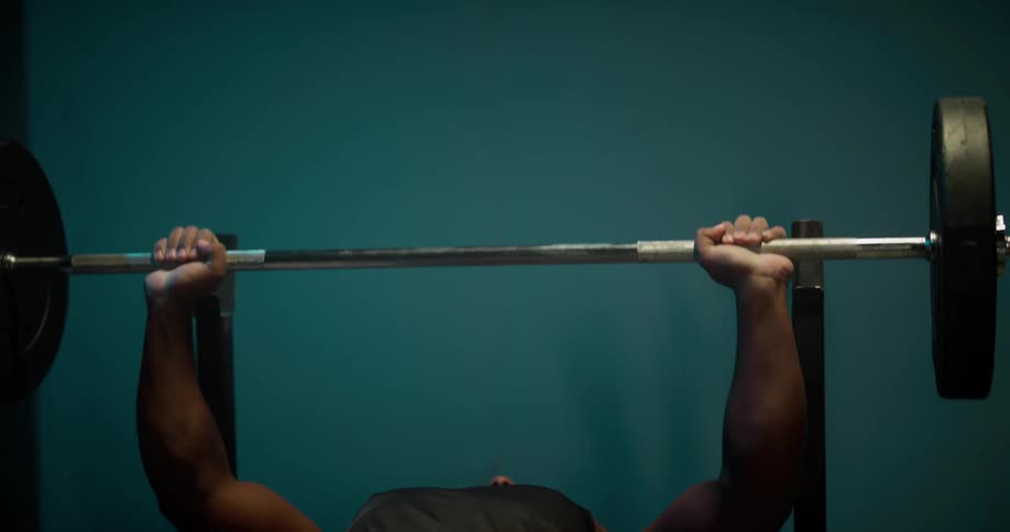 A man lifts weights on a weight bench indoors