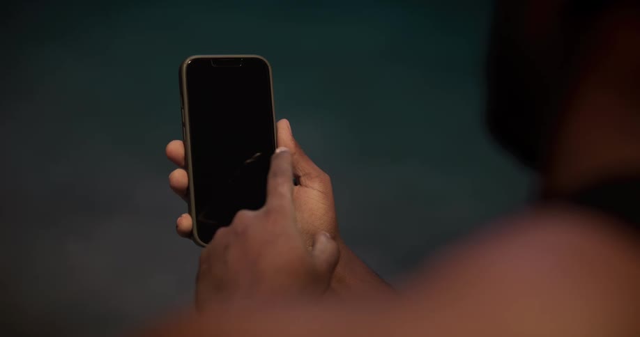 A man is holding his cell phone and moving his finger across the screen