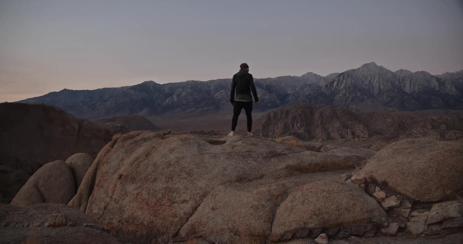 A man jumps onto rocks while hiking through a canyon