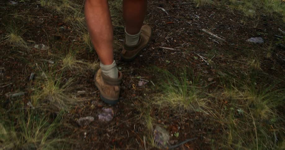 A person wearing boots walks through a field during the day
