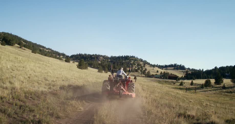 Tractor drives on country road near the farms