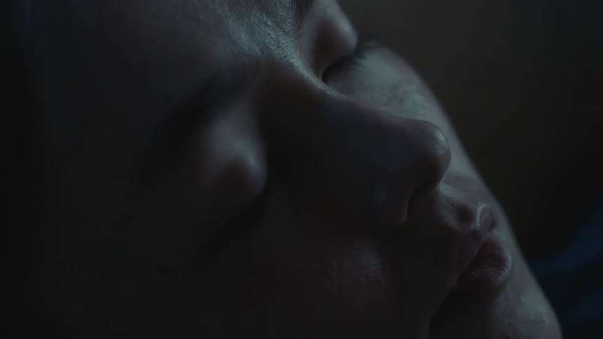 Woman moves her mouth while she dreams in dim room