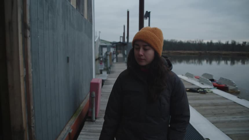 A teenage girl is seen walking near facilities on a lakeside