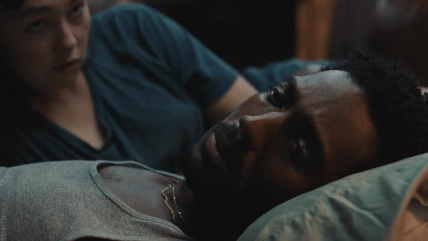 A woman talks to a sad man on the bed