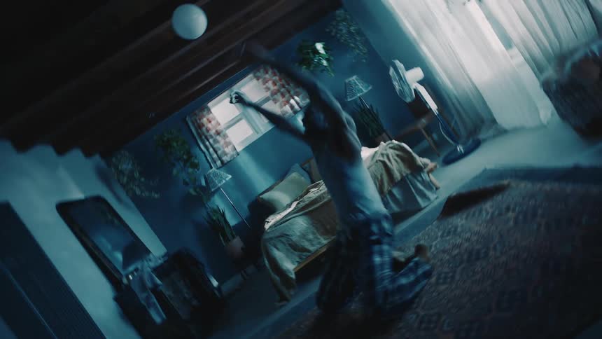 Twisting footage of a man wearing pajamas dancing on the bedroom