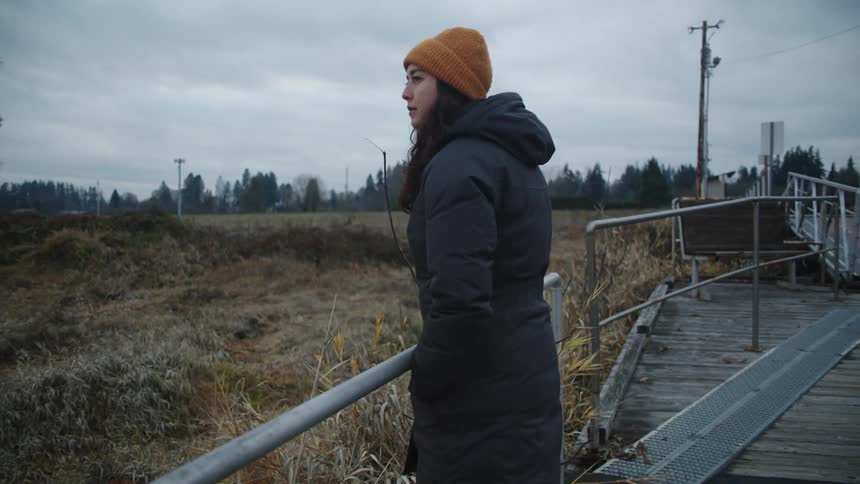 Young woman standing on an abandoned boardwalk in the countryside