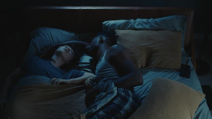 A couple are sleeping in bed