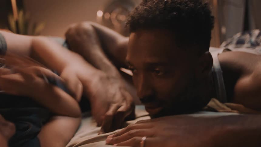 A man and woman lie in bed and laugh and talk
