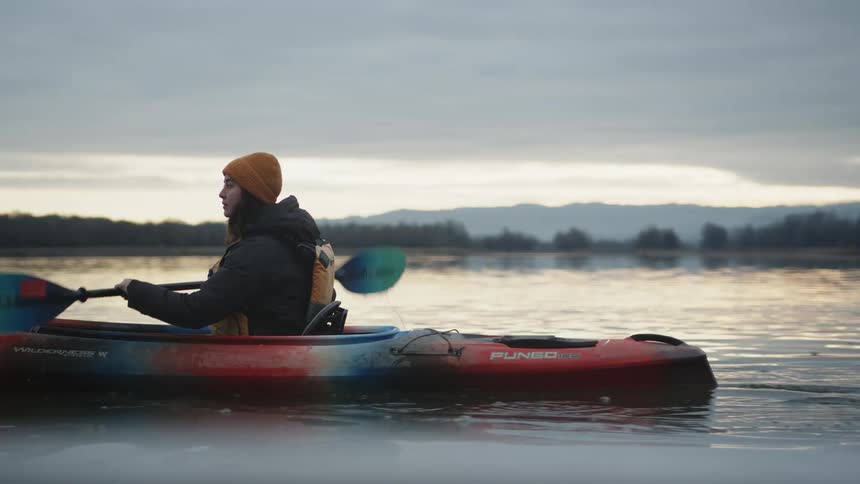 A teenage girl paddles a canoe in a lake
