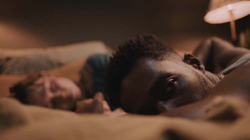 Faces of a couple resting in the bed at home facing the camera