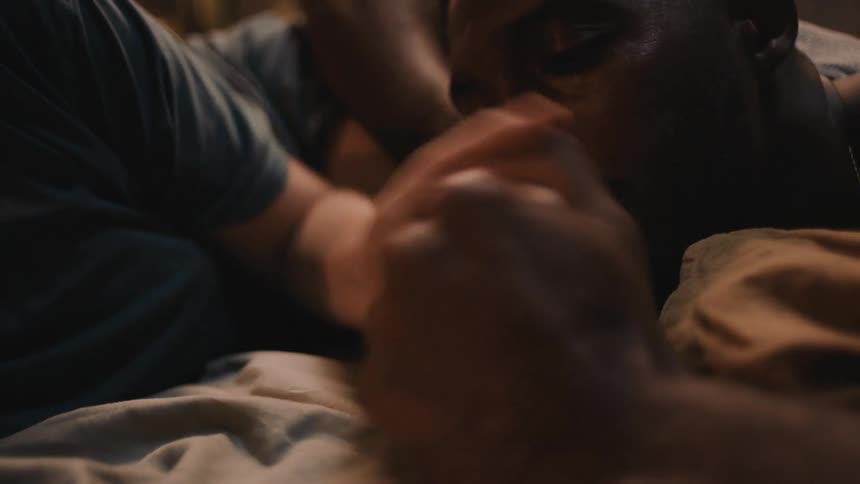 A couple thumb wrestle while lying in bed