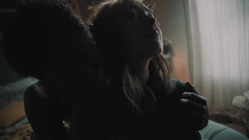 Man back hugs and comforts woman as they sit on bed