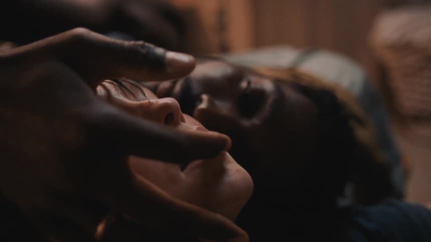 Man playing with the lips of his partner while resting on the bed at home