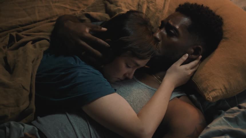A couple cuddle in bed