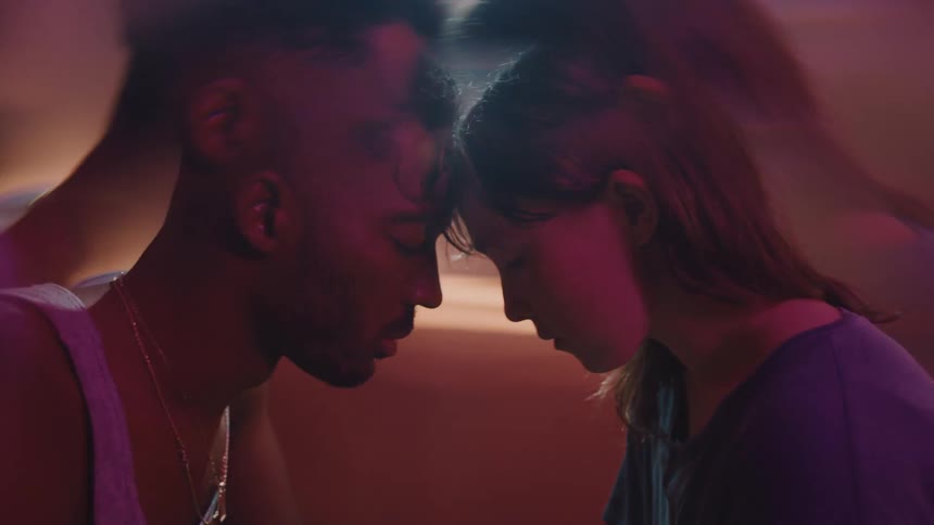 A couple touch foreheads while sitting in a room
