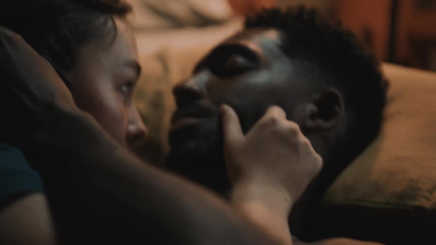 Couple cuddling and caressing each others faces while laying in bed