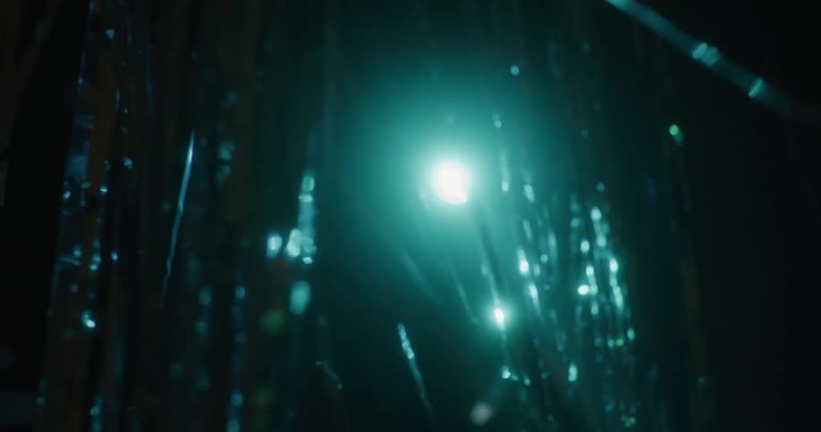 Silver tinsel foil decoration shimmering under a blue light on a dark room