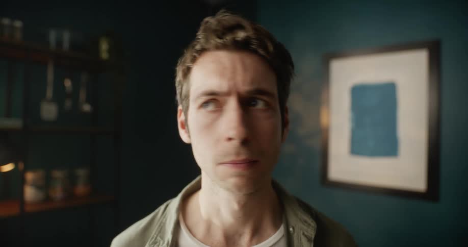 Man standing on a room looks side to side and then looks at the camera
