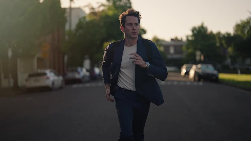 A nervous looking young man runs down a neighborhood street