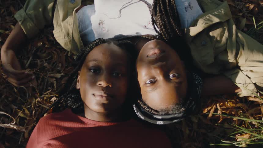 Top down view of the faces of two young people laying on the ground looking at the camera