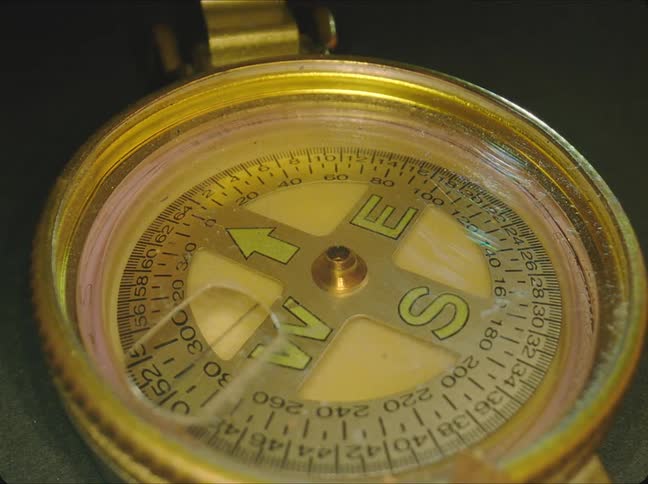 A brass compass sits with its cover open