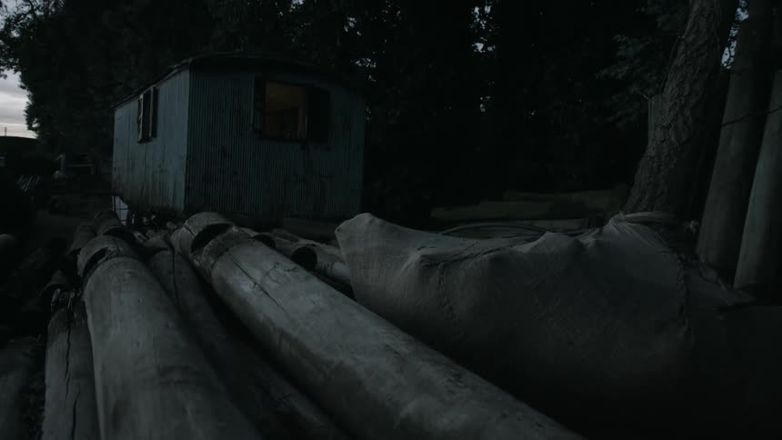 A stack of logs are by the trailer