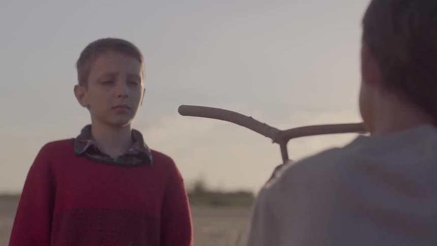 A boy points a stick at another boy