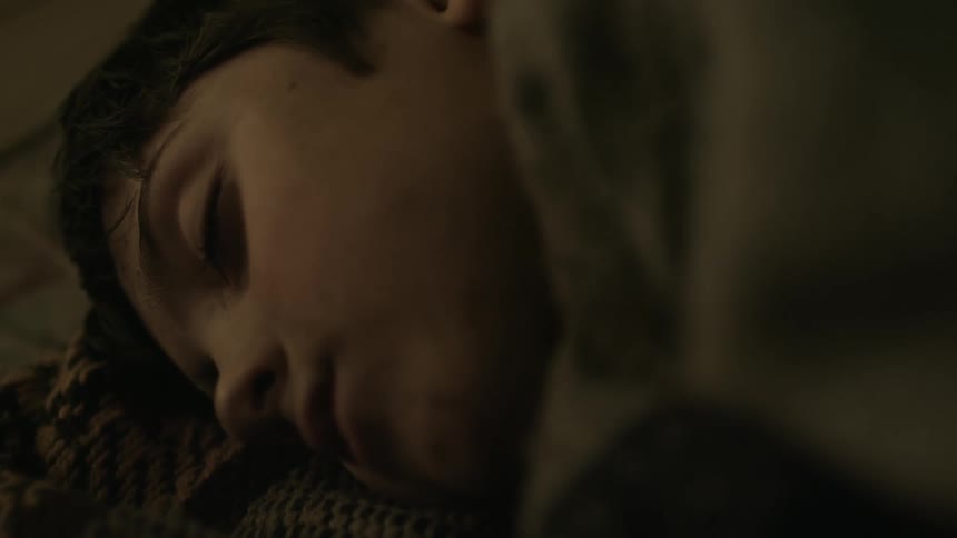 A boy is lying down sleeping on a blanket