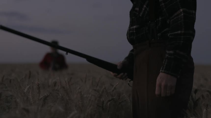 A man lifts his rifle on the field