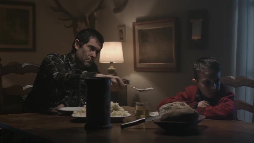 Father serves mashed potatoes to boy who is ignoring him