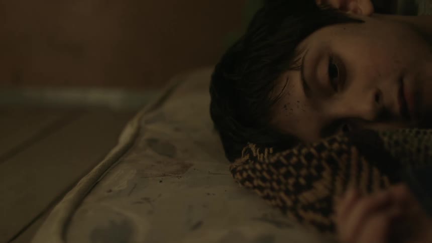 A boy lying on a cushion with a blanket