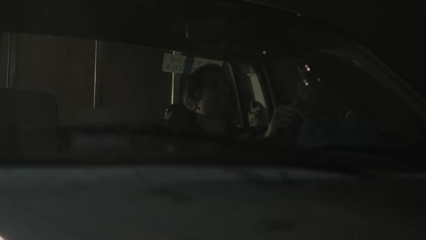 Man sits in truck at night tapping the steering wheel while listening to music