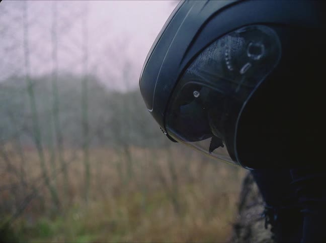 A young person is wearing a helmet and is in the woods around the middle of the day