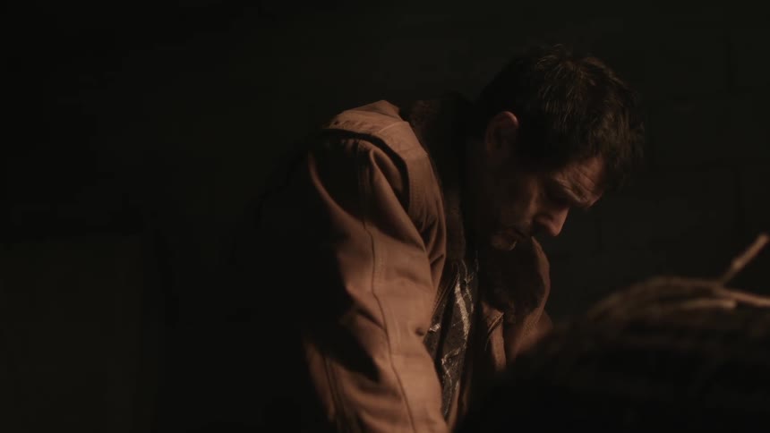 A man looks down and cries while standing outside alone