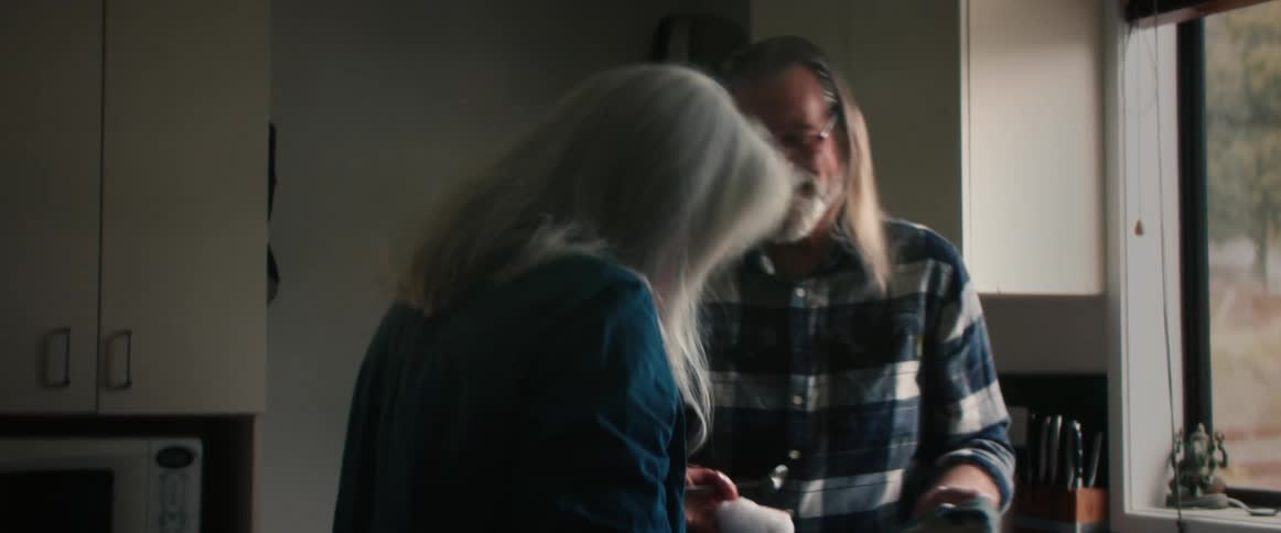 Happy mature couple talking and laughing in the kitchen at home