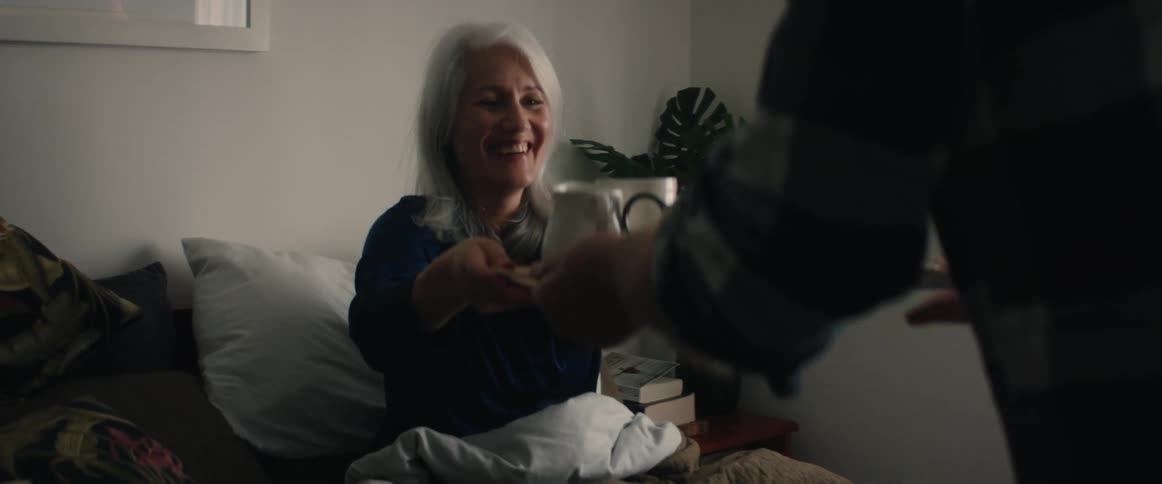 A man giving food to a woman for breakfast in bed