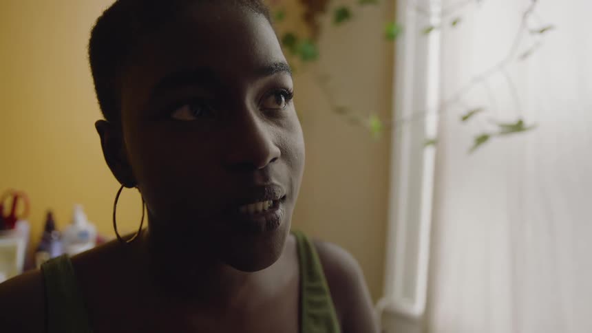 Close up of a young woman sitting at home in her bedroom talking
