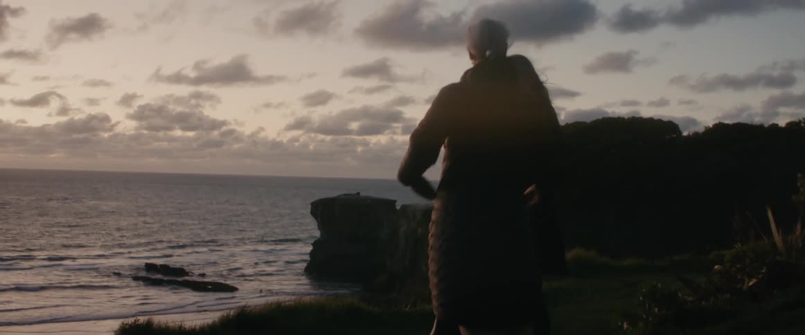 A man and woman standing on the coast