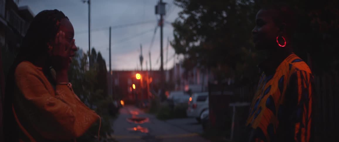 Two women excitedly talk with one another in a neighborhood street