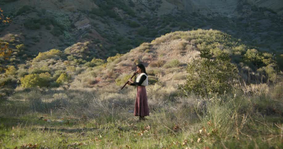 There is a young woman that is standing in the forest area