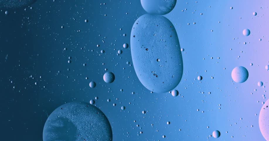 Blobs and bubbles of translucent liquid gently merging over a blue and magenta background