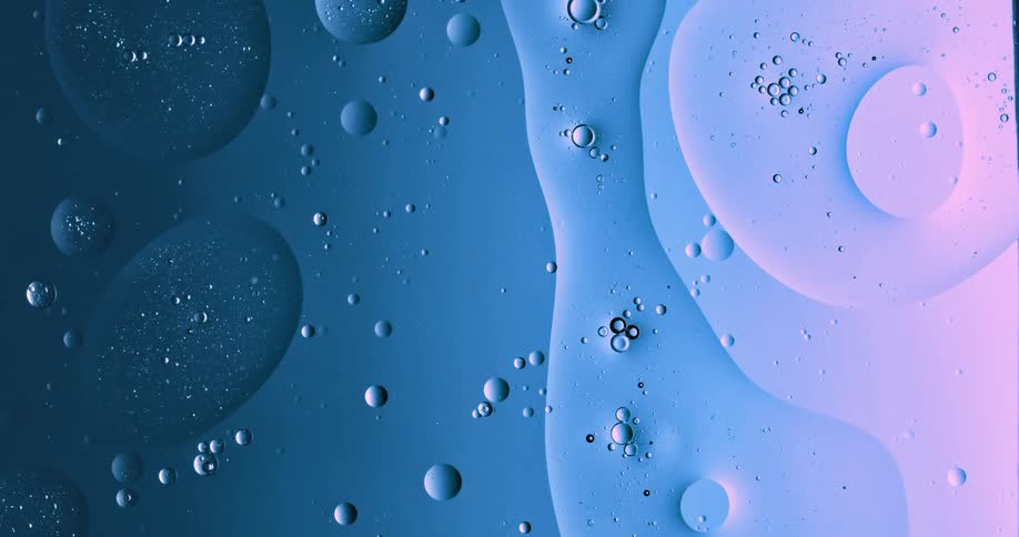 Blobs and bubbles of translucent liquid gently flowing over a blue and magenta background