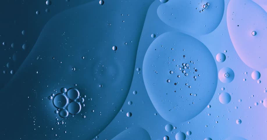 Blobs and bubbles of translucent liquid gently flowing over a blue and magenta background