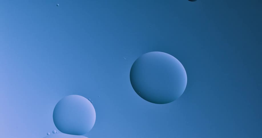 Orbs slowly move in a light blue environment as two spheres merge into one when they touch