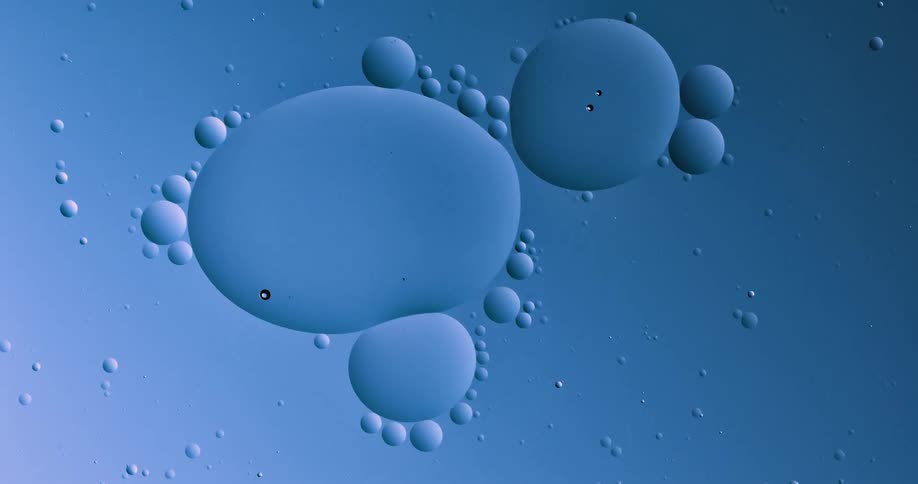 Round bubbles of various sizes floating on a blue and magenta liquid