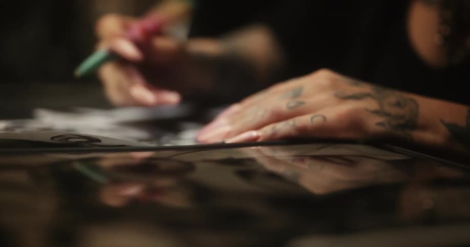 Tattoo artist sketching on a piece of paper with a pen